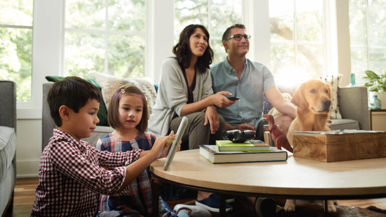 Family in living room with the children playing on a tablet