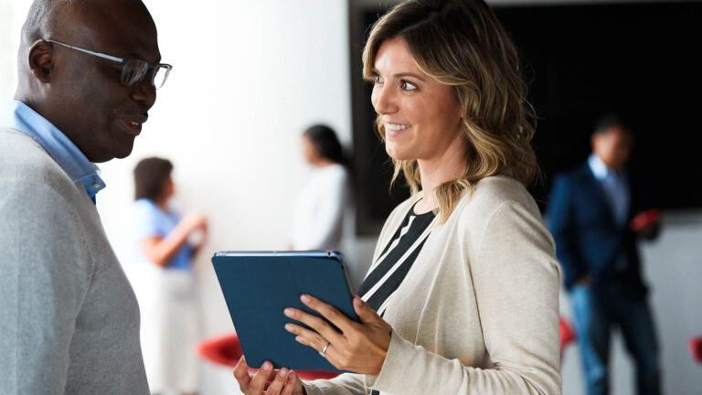 Man and woman discuss something from a tablet that the woman is holding