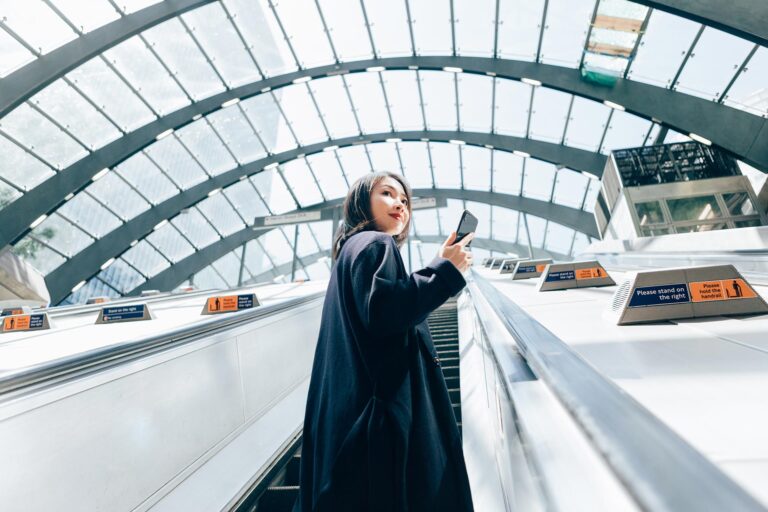 Young Business Woman Using Smart Phone, Riding An Escalator