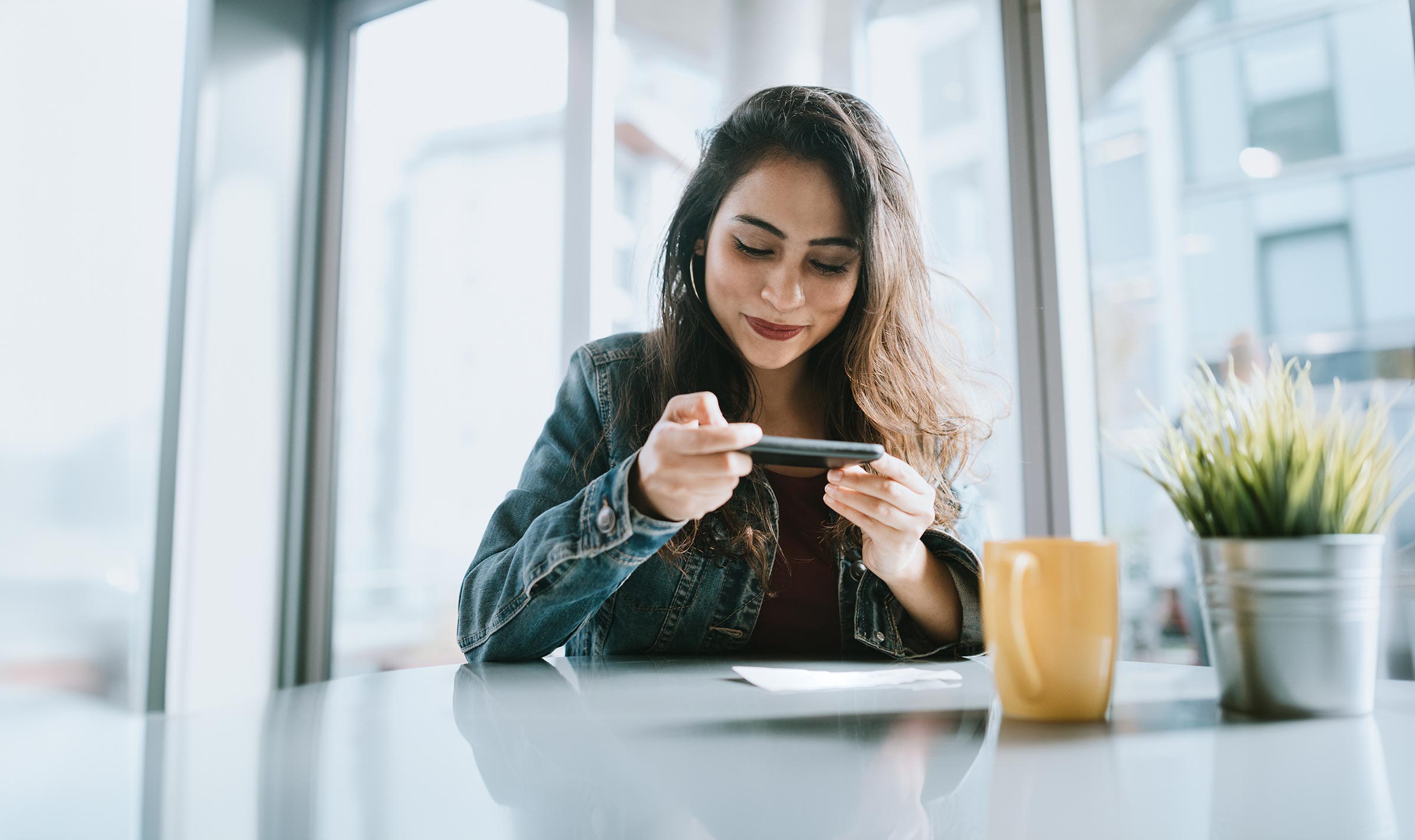 Woman in cafe taking photo of check for mobile deposit