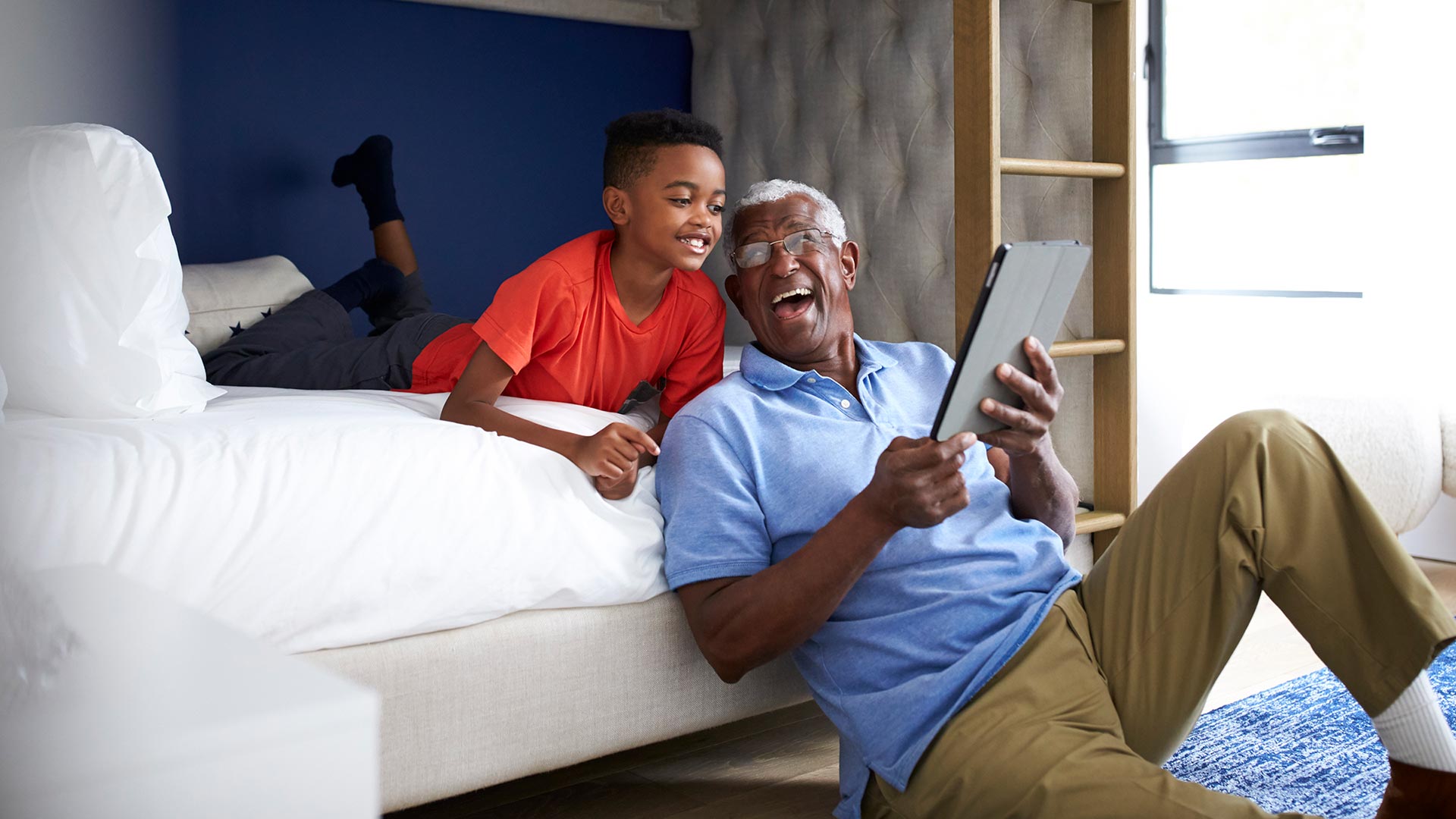 Grandfather and grandson share a laugh over a tablet