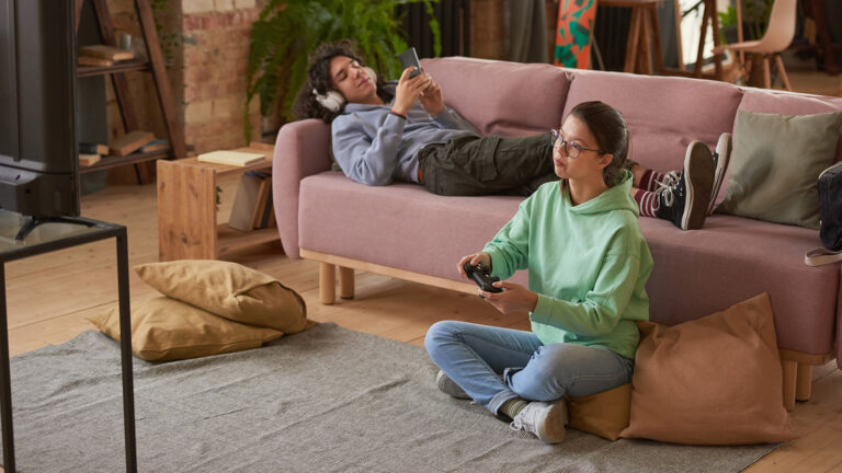 Two teenagers playing video games at home