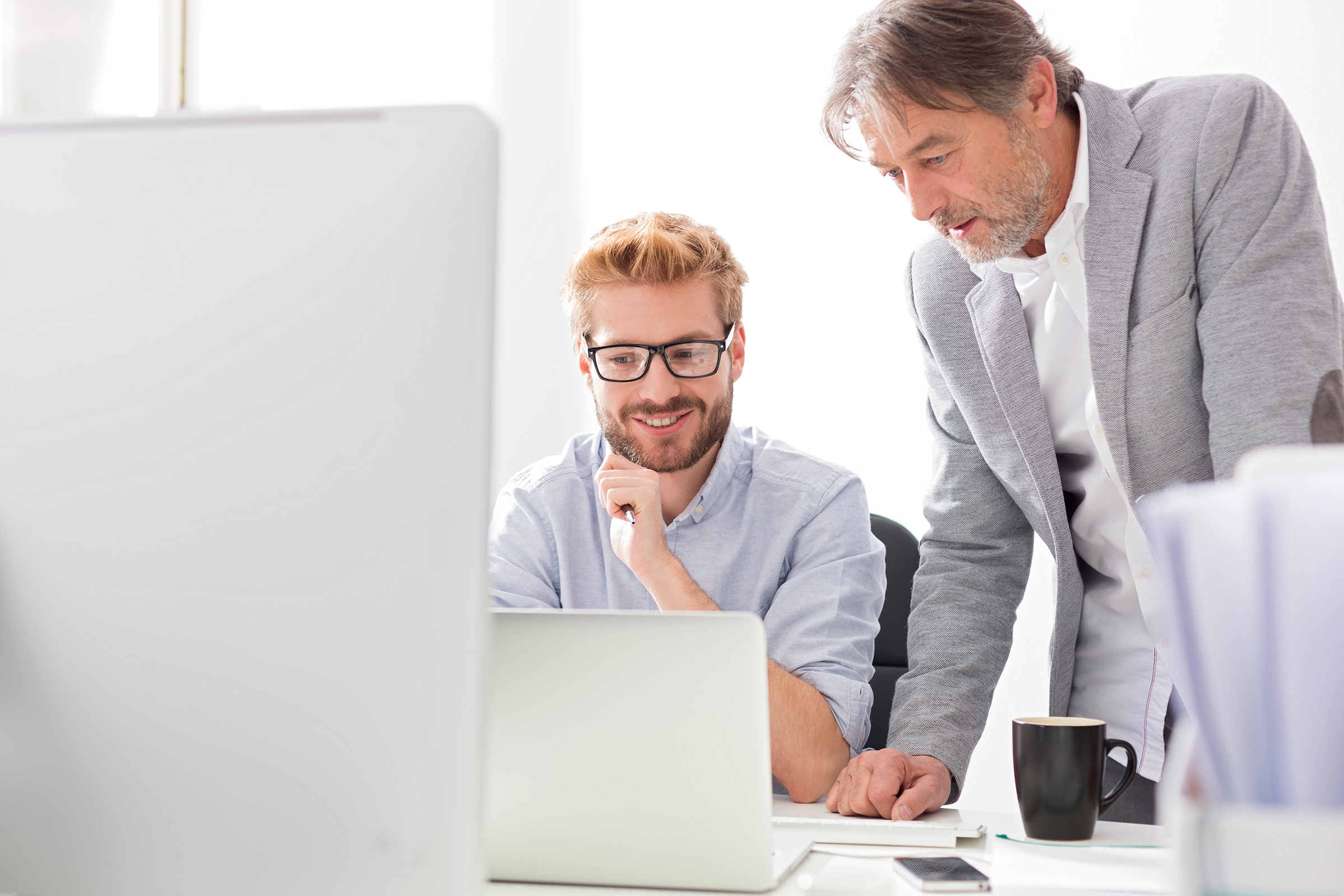 two businessmen with laptop at desk