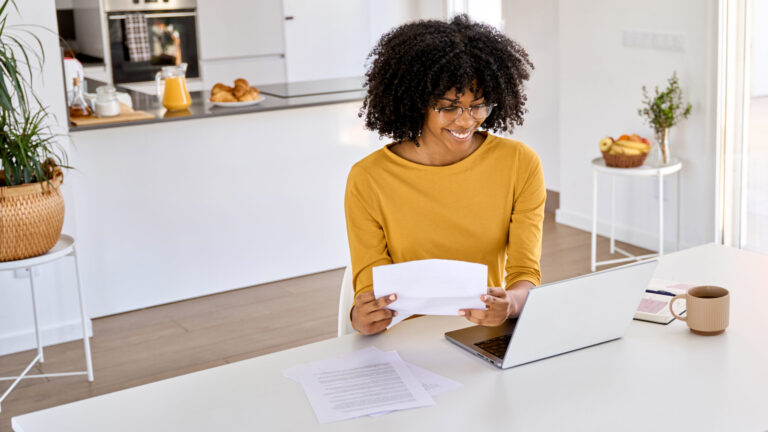 young happy african woman checking paper laptop