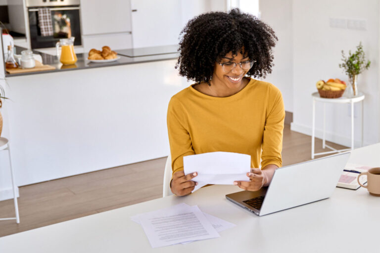 young happy african woman checking paper laptop